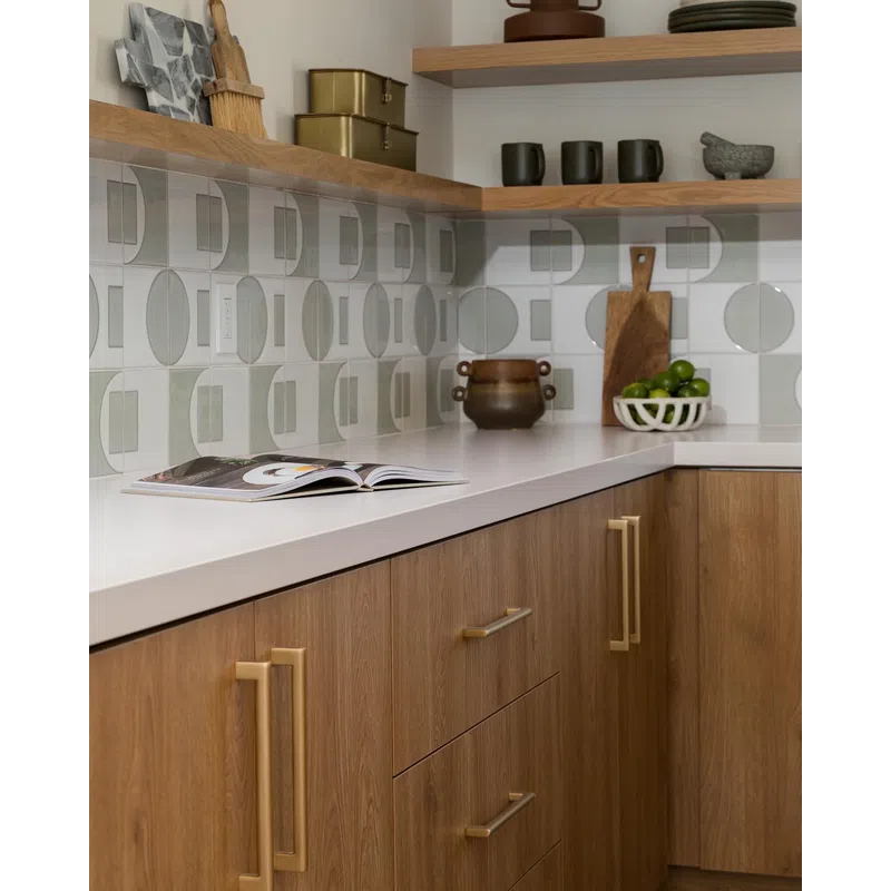 Modern kitchen corner with wooden cabinets, white countertop, geometric backsplash tiles, and open shelves.