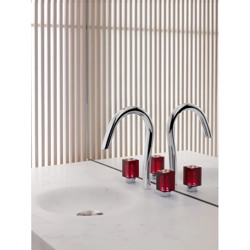 Modern bathroom sink with chrome faucet and red square handles against a striped beige wall and mirror.