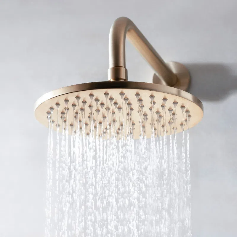 Brushed metal rainfall showerhead with water flowing against a light gray wall background.