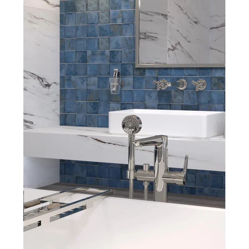 Modern bathroom with blue tiled wall, white marble surfaces, chrome faucet, and rectangular sink under mirror.