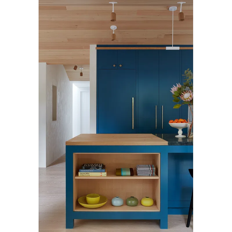 Modern kitchen island with blue cabinetry, wooden countertop, decorative vases, and books on open shelves