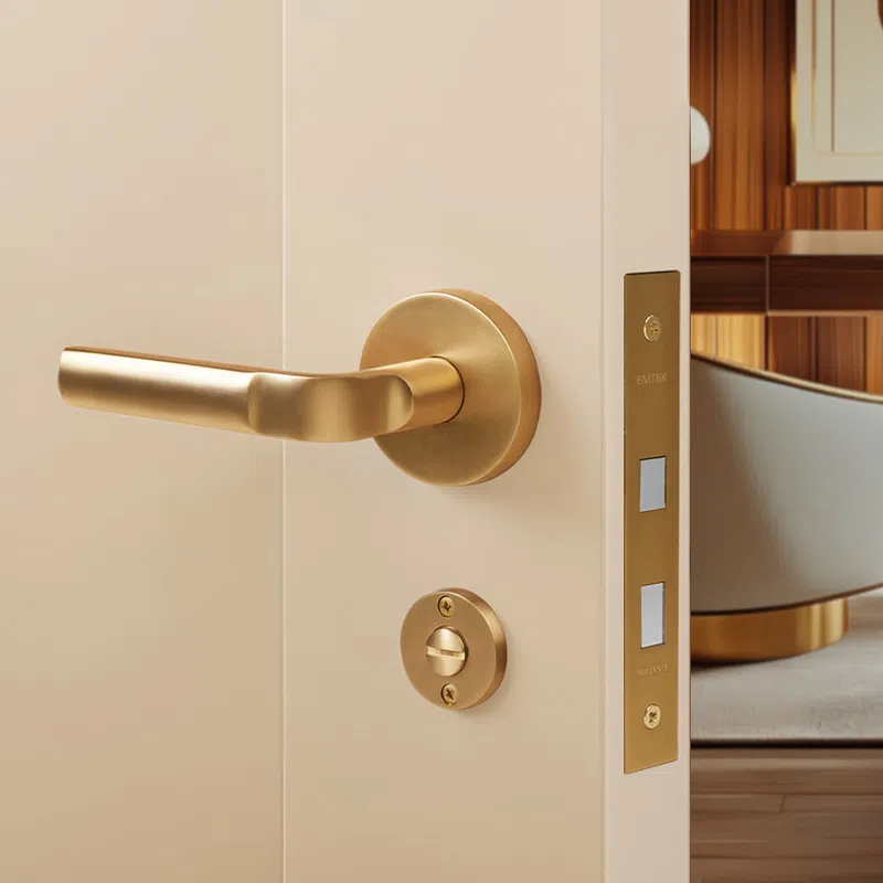 Modern gold door handle and lock on a beige door with a stylish interior background.