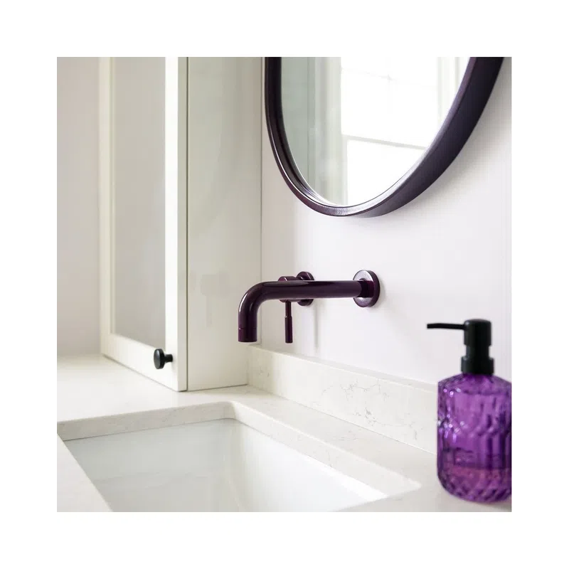 Modern white bathroom sink with wall-mounted dark faucet and purple soap dispenser on marble countertop.
