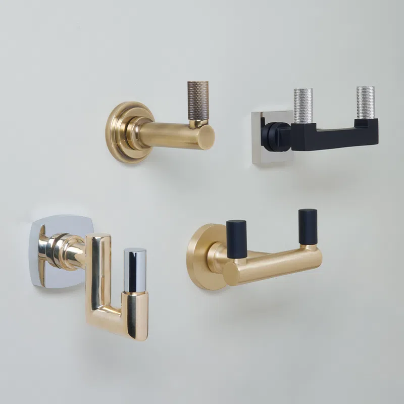 Four modern wall-mounted coat hooks in gold, black, and chrome finishes on a white background.