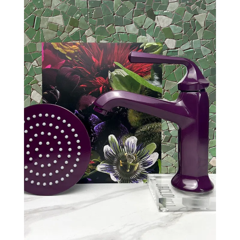 Purple faucet and matching showerhead on a marble surface with floral and mosaic green tile background.