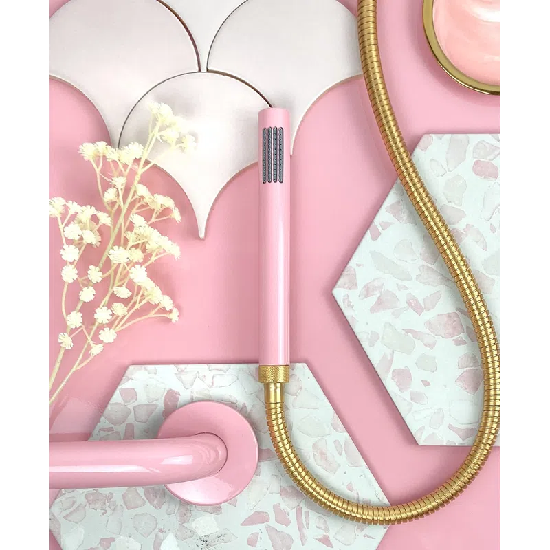Pink and gold shower head with floral decor on pink and terrazzo tile background