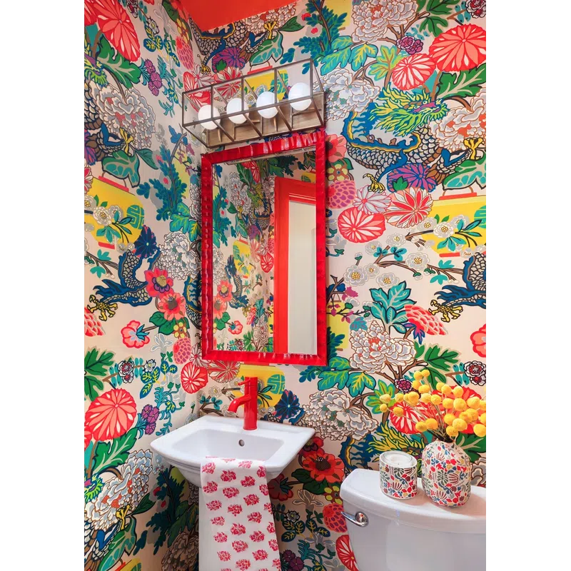 Vibrant bathroom with floral and dragon wallpaper, red framed mirror, red faucet, and patterned decor accents.