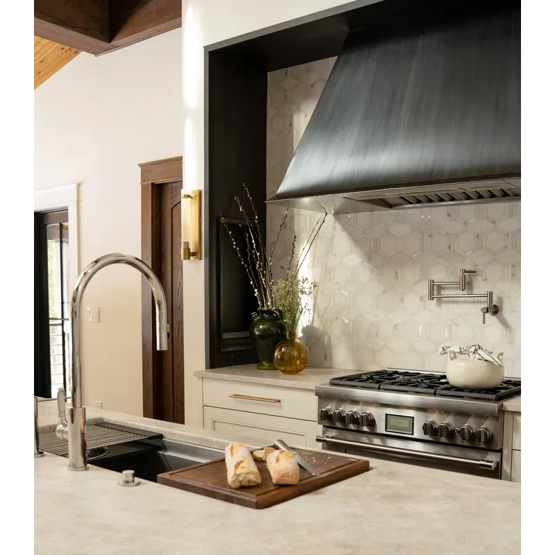 Modern kitchen with stainless steel stove, stylish hood, marble countertop, and freshly sliced bread on cutting board