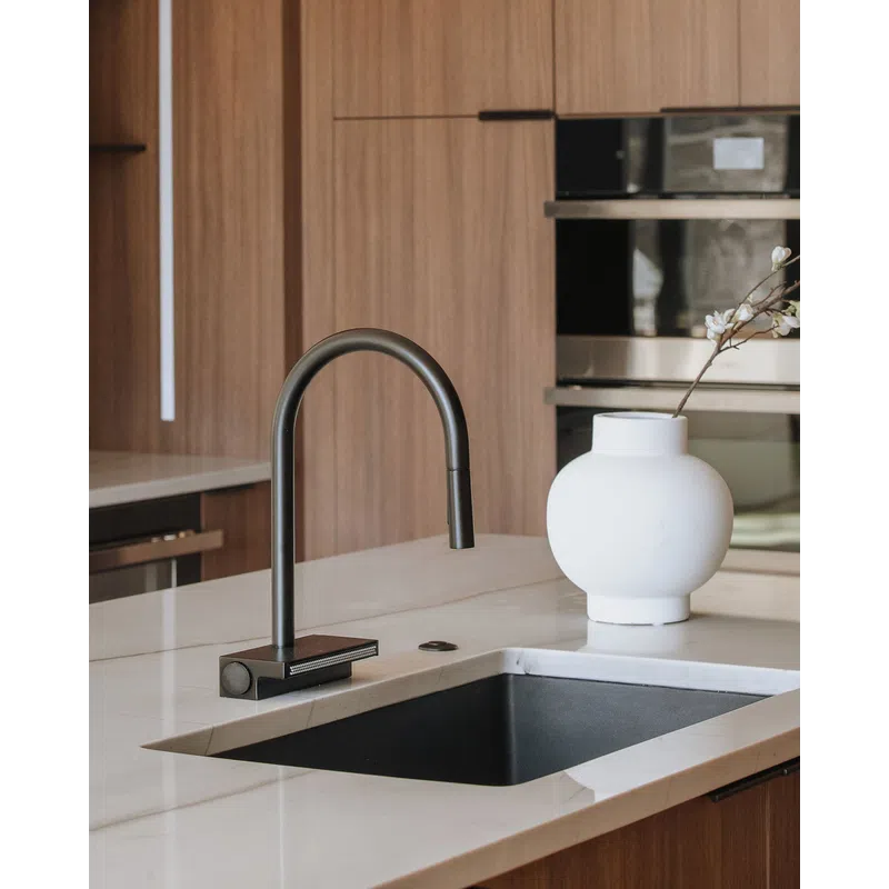 Modern kitchen sink with black faucet and white vase on marble countertop in a wood-paneled kitchen.