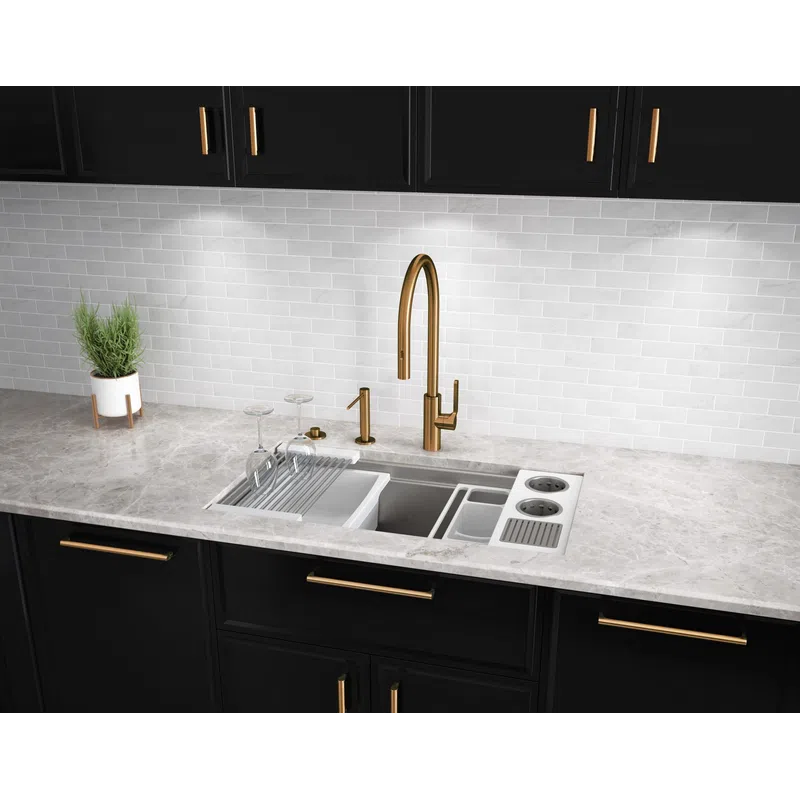 Modern kitchen sink with gold faucet, black cabinets, marble countertop, and white subway tile backsplash.
