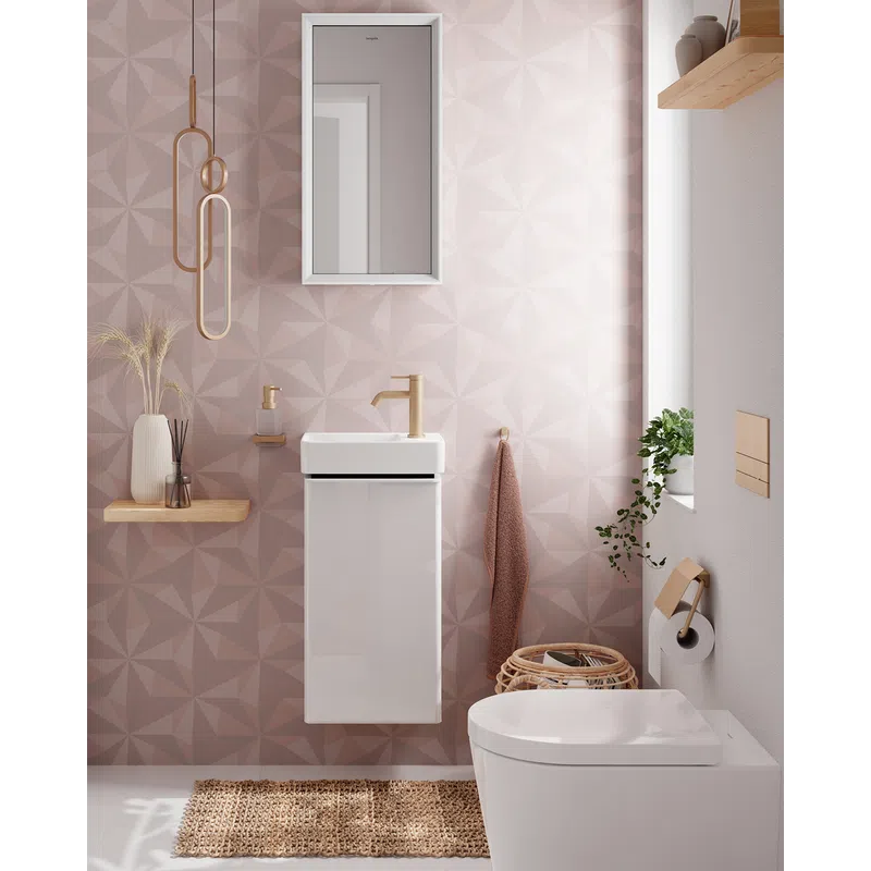 Modern bathroom with geometric pink wall tiles, white floating sink, toilet, and natural decor accents.