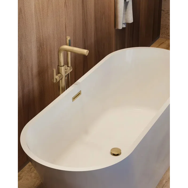 White freestanding bathtub with modern gold faucet against wooden wall in a bathroom.