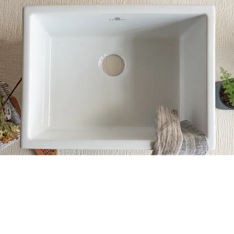 Top view of a white rectangular ceramic sink with a center drain and a gray towel draped over the edge.