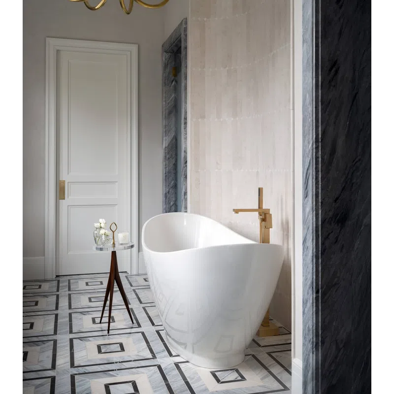 Modern white freestanding bathtub with gold faucet, geometric tiled floor, and minimalist decor in luxury bathroom.