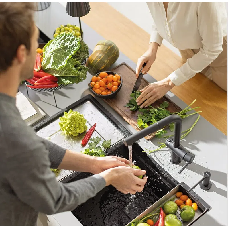 Couple washing and chopping fresh vegetables in a modern kitchen with various produce on the counter
