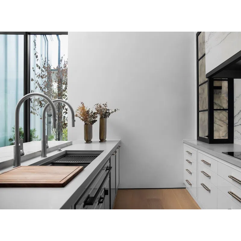 Modern kitchen with white cabinets, marble backsplash, wooden floor, dual sinks, and sleek stainless faucets.