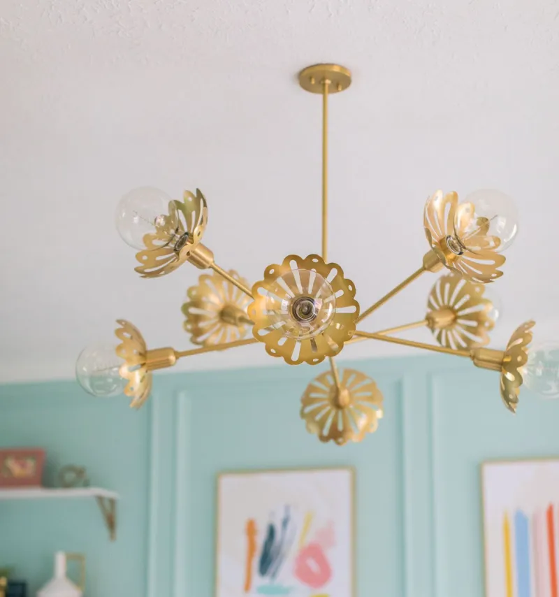 Stylish gold chandelier with floral design and glass bulbs, enhancing a bright, modern interior.