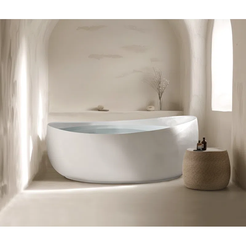 Modern white freestanding bathtub in a minimalist arched bathroom with natural light and woven side table.