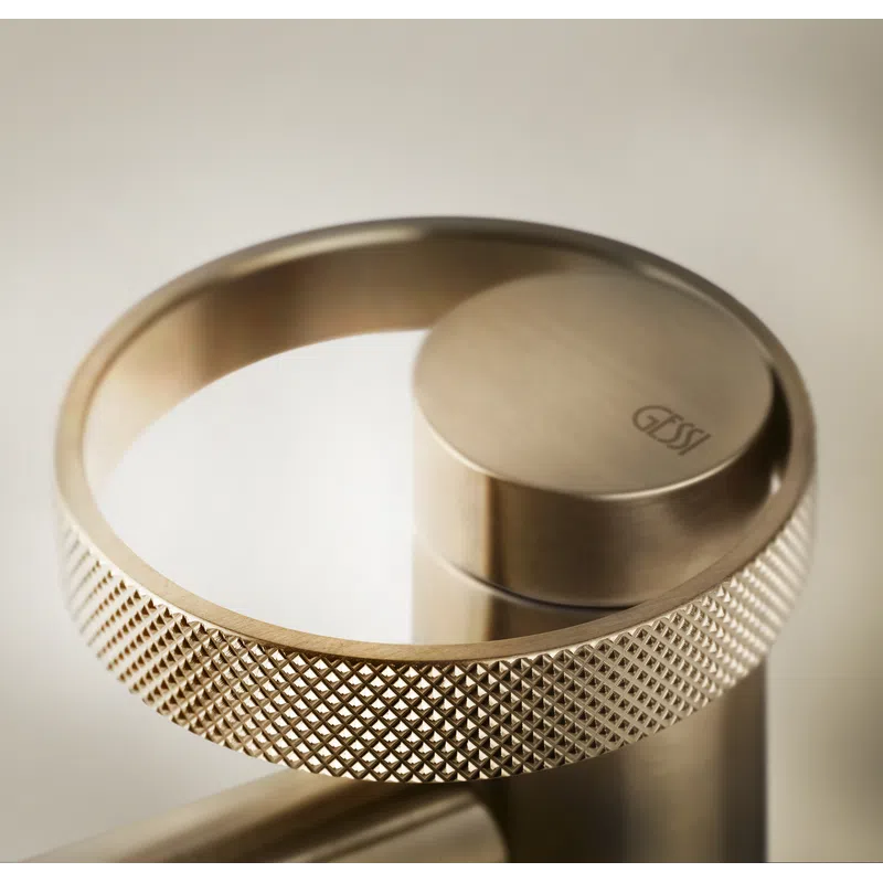 Close-up of a textured metallic ring handle on a sleek, modern Gessi faucet in brushed gold finish.
