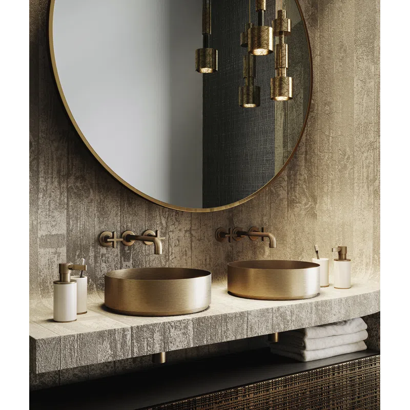 Modern bathroom with round gold sinks, wall-mounted gold faucets, large circular mirror, and hanging gold pendant lights.