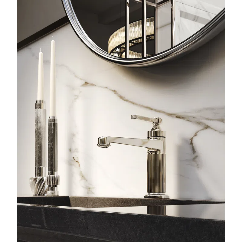 Modern bathroom faucet with ribbed metallic design, black countertop, marble backsplash, and two tall candles.
