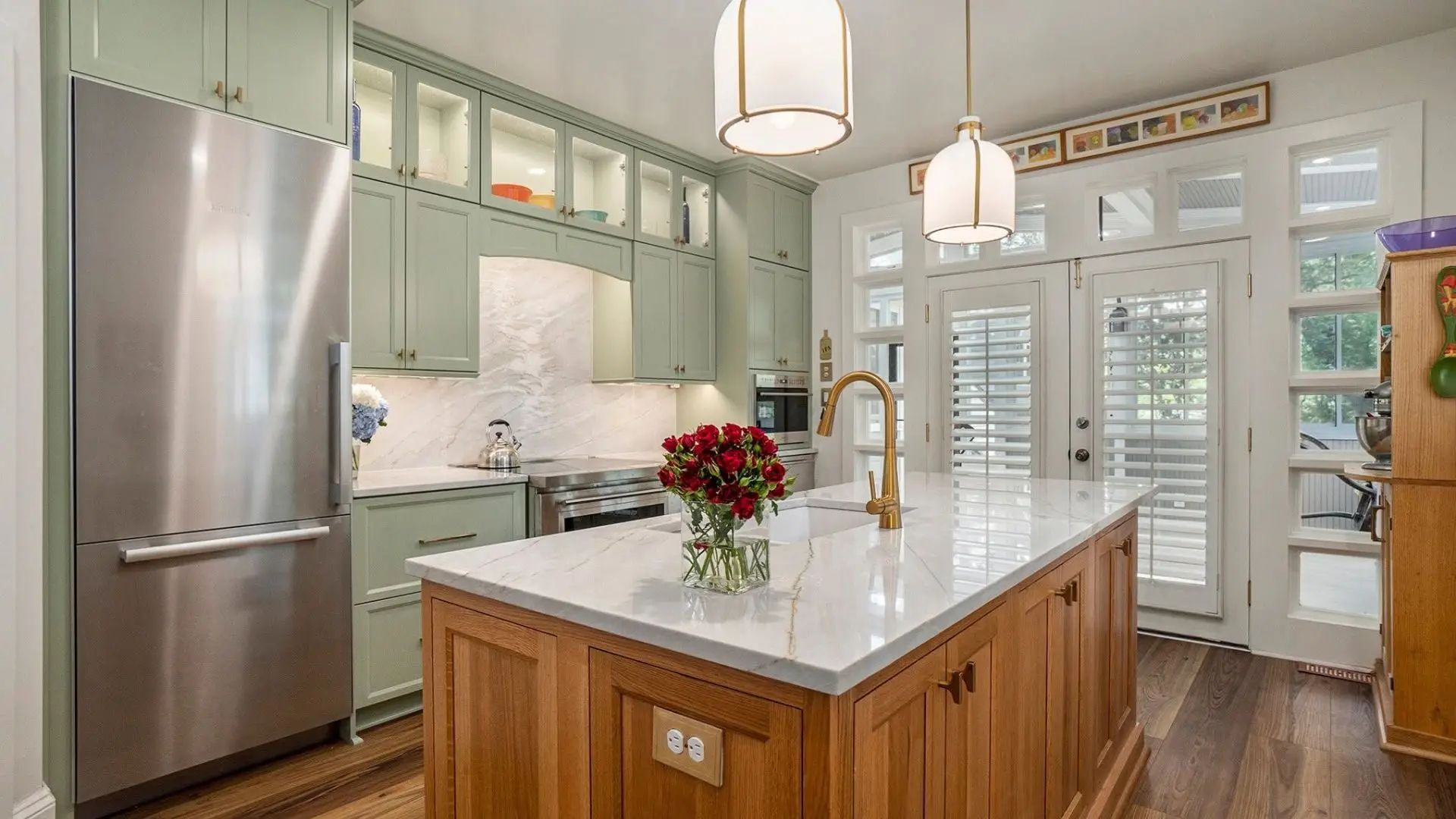 Modern kitchen with green custom cabinetry, stainless steel appliances, and pendant lighting