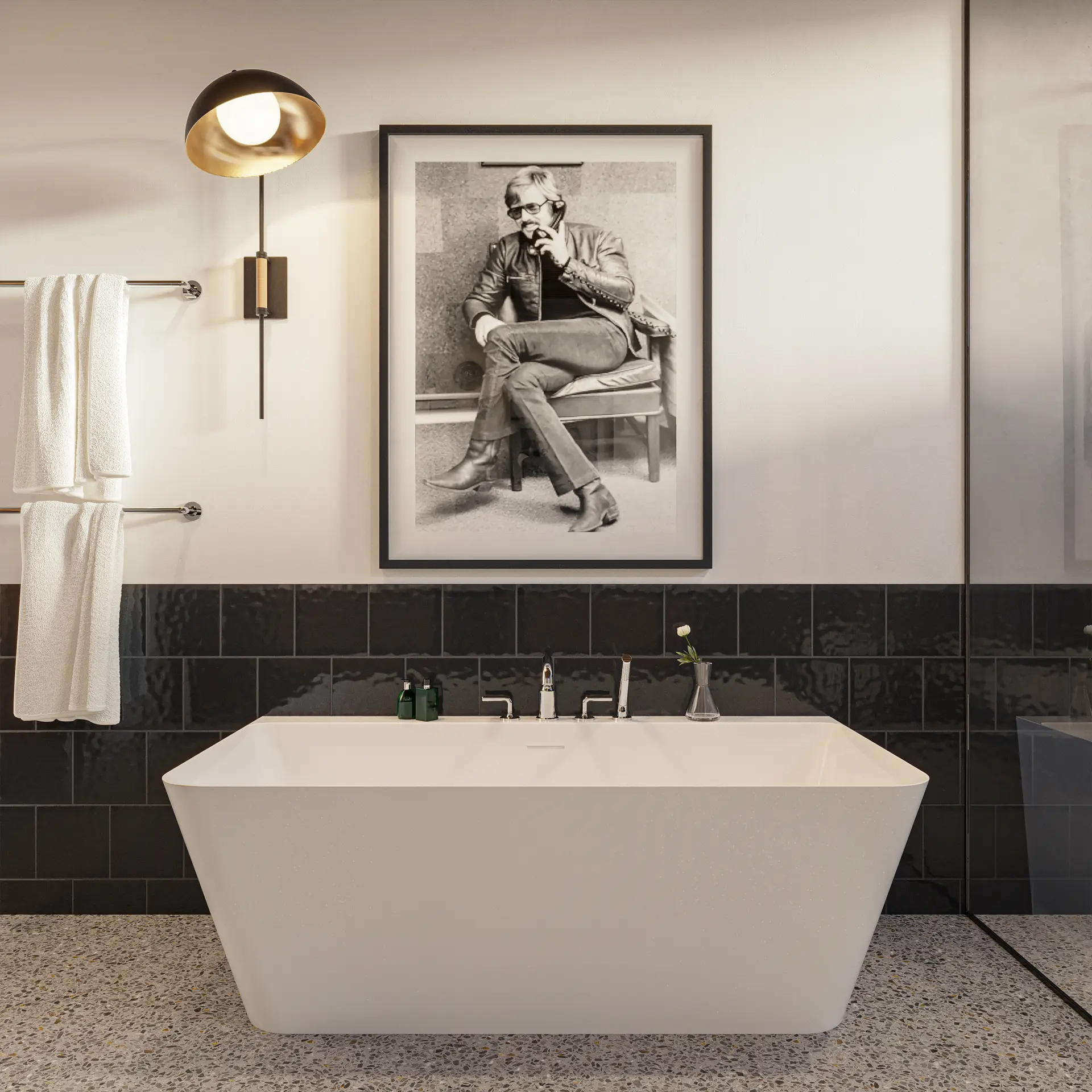 Crosswater Taos freestanding square bathtub with deck faucet against black tile under a framed portrait.