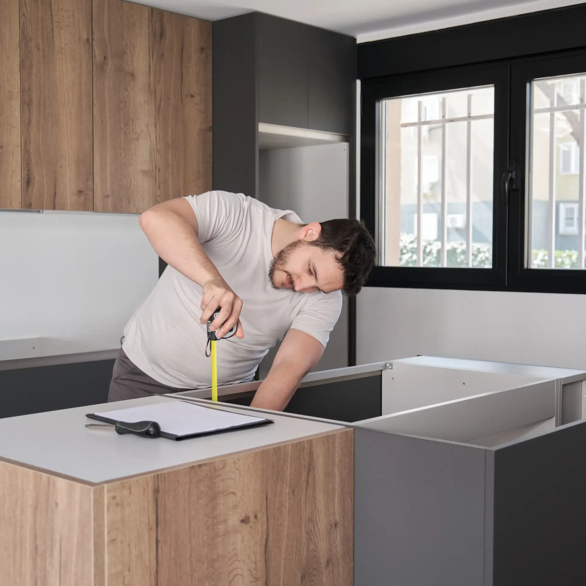 Team member measuring cabinetry on site with a tape measure
