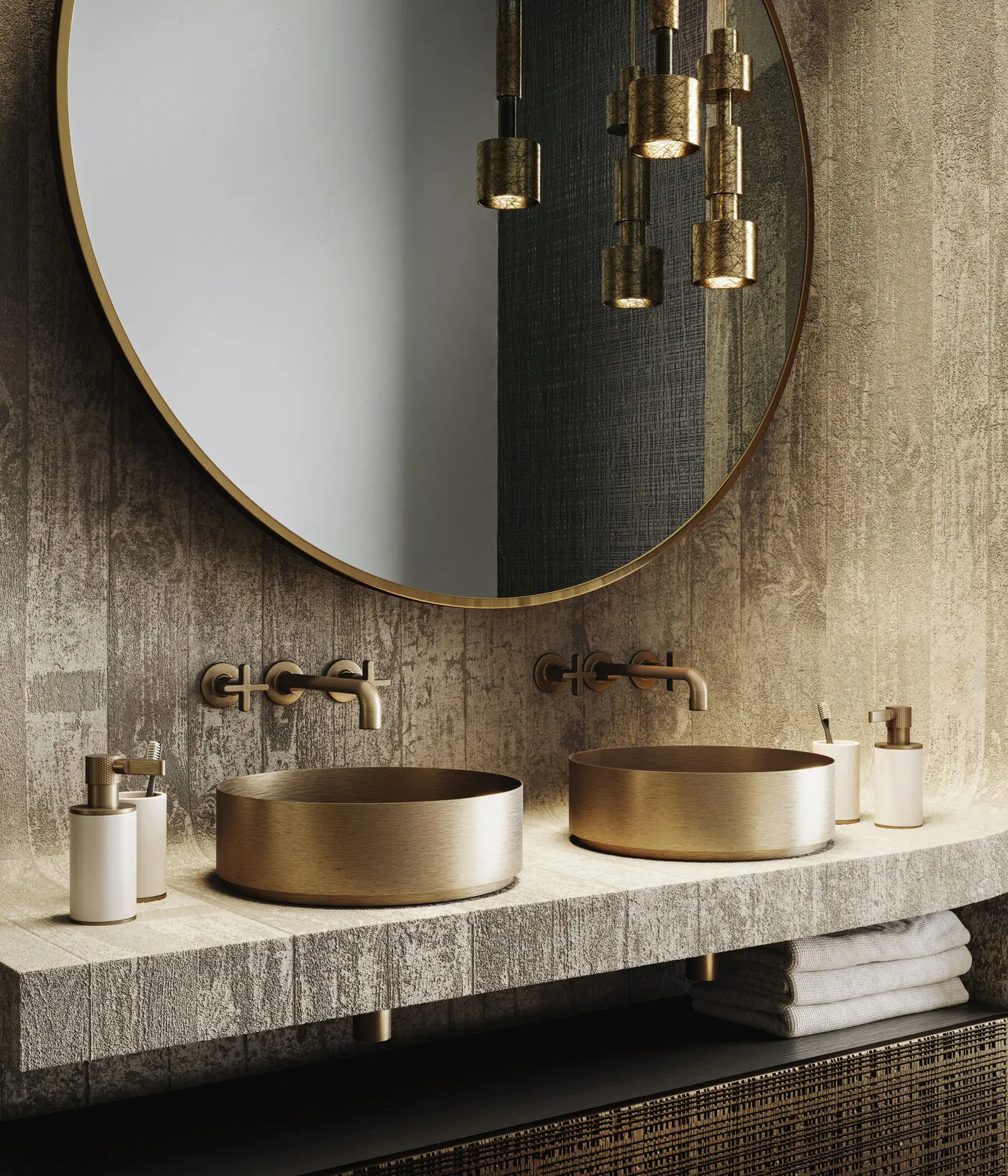 Brushed brass Gessi vessel sinks and wall-mounted faucets beneath a round brass mirror in a textured stone bathroom.