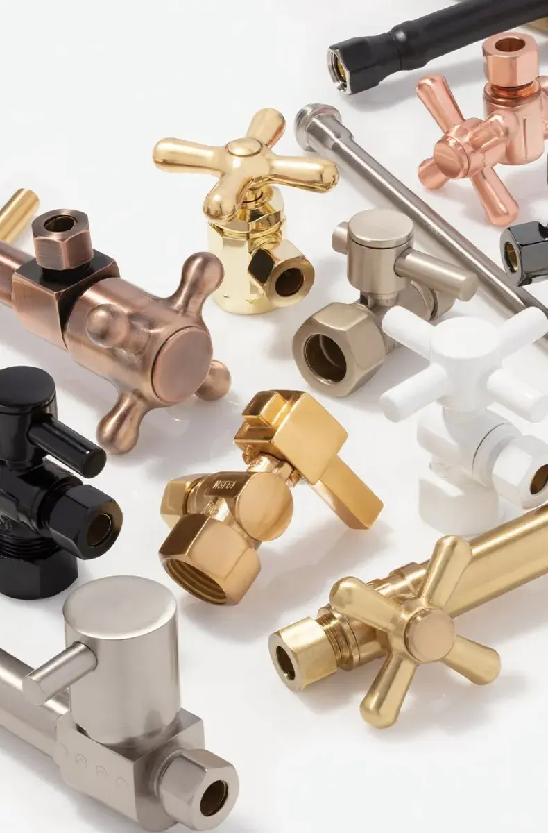 Various metallic plumbing valves in gold, silver, black, bronze, and white on a white surface.