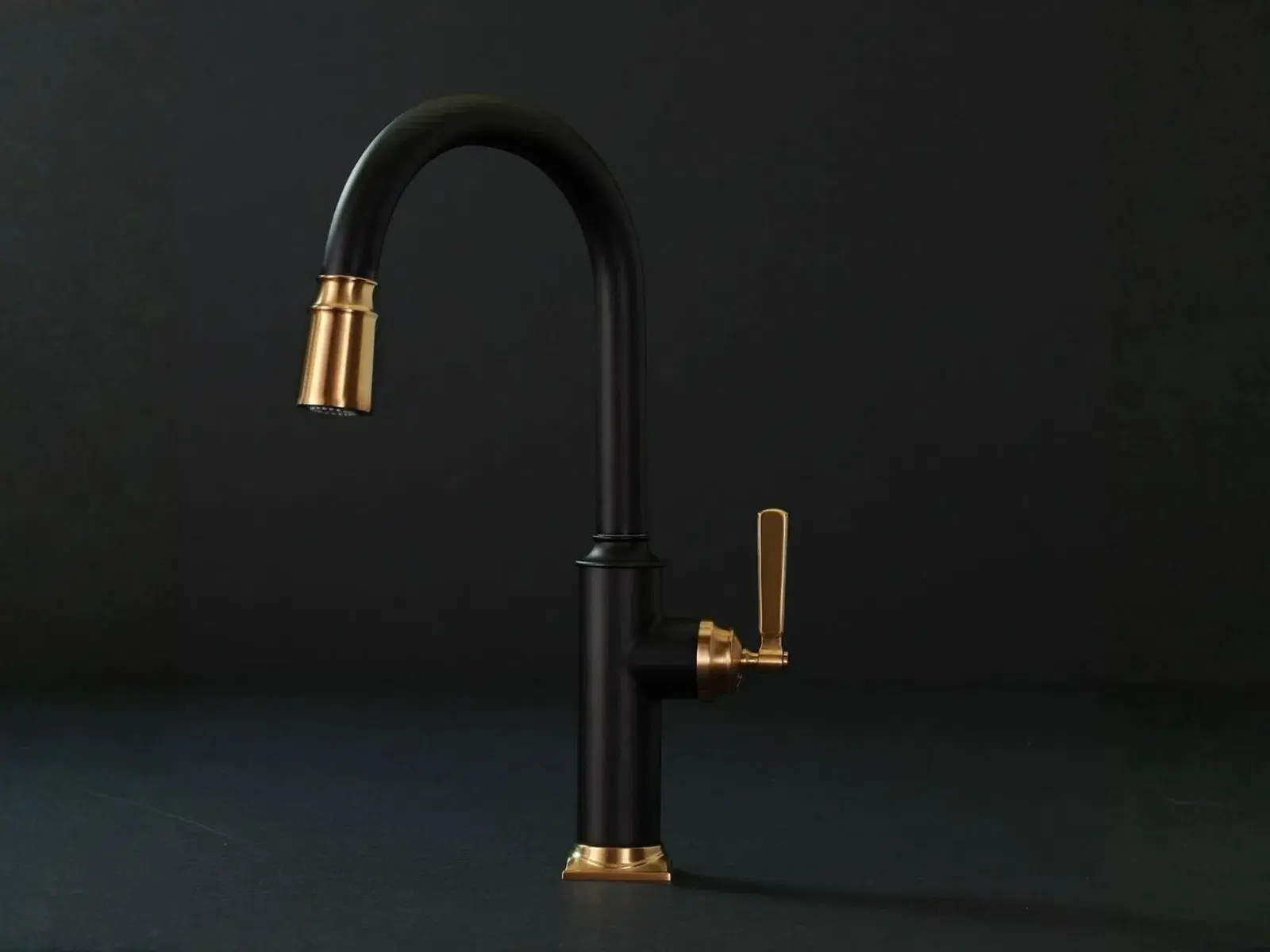 Matte black kitchen faucet with gold accents on handle and spout against a dark background