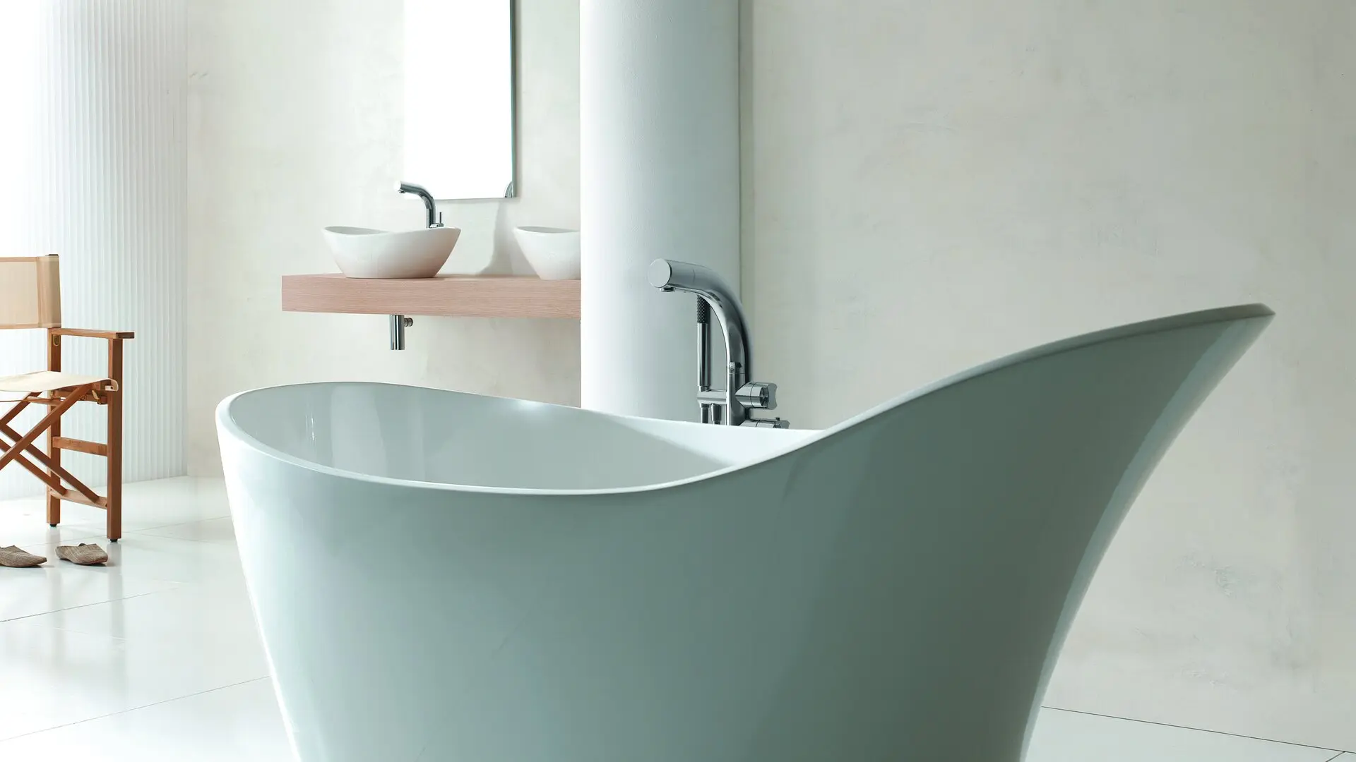 Close-up of a sculptural sage-green freestanding bathtub with a curved rim in a minimalist bathroom.