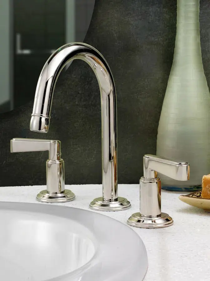 Polished nickel Watermark widespread bathroom faucet with lever handles on a white marble countertop.